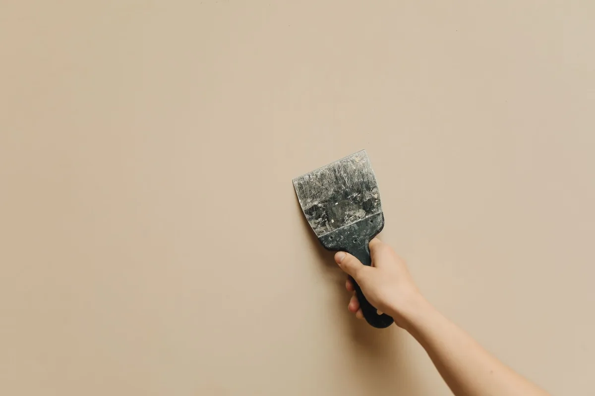 Outils de plâtrage et de peinture préparés sur un sol près d'un mur endommagé