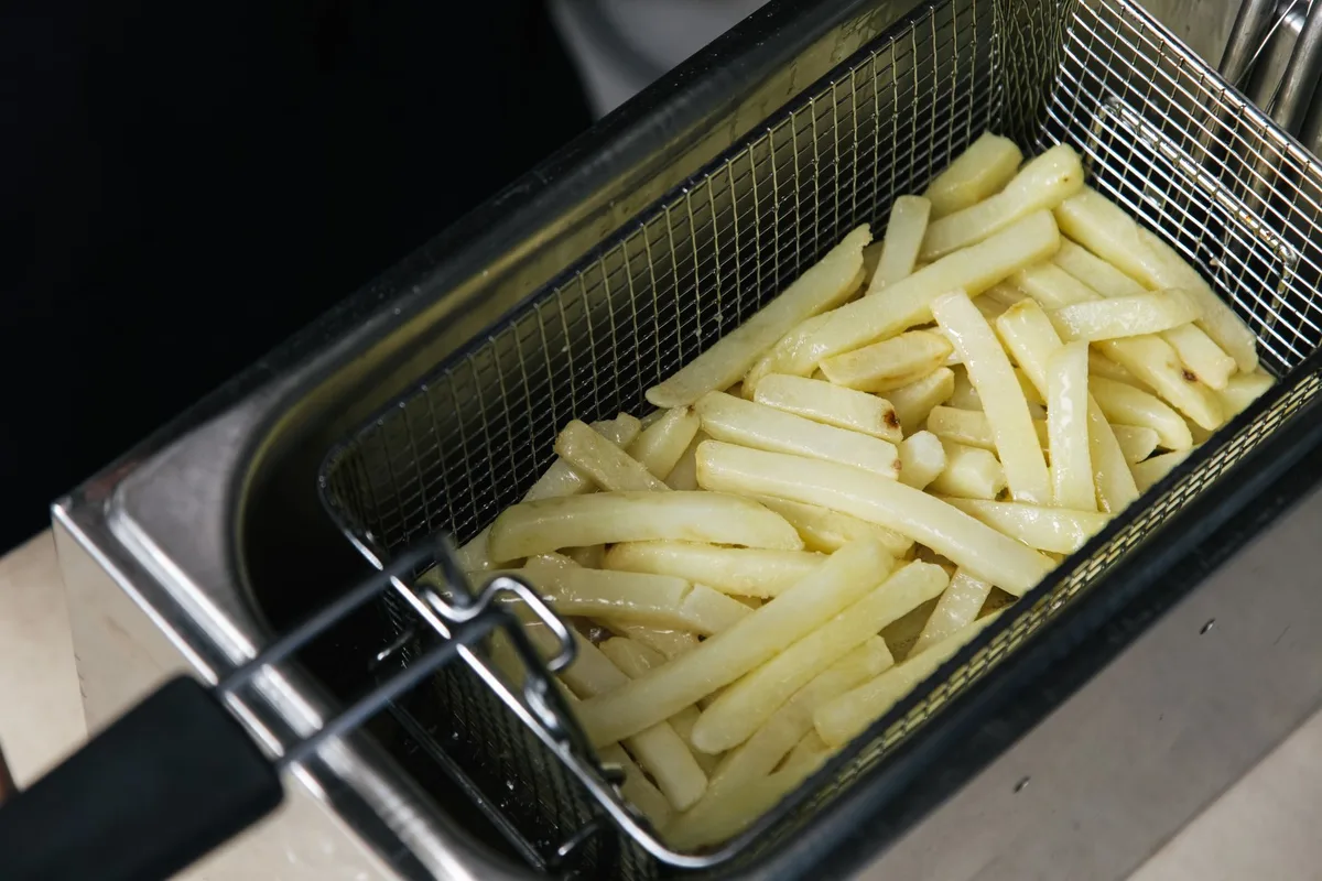 Assortiment de légumes et frites dorés dans un panier de friteuse sans huile